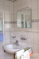 ein Badezimmer mit einem Waschbecken, einem Spiegel und Handtüchern in der Unterkunft Pension Waldwinkel in Lenzkirch