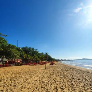 a sandy beach with a row of trees and the ocean at POUSADA POLONINI - Localização ótima in Piúma