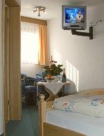 a bedroom with a bed and a tv on the wall at Pension Waldwinkel in Lenzkirch
