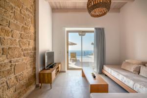 a living room with a couch and a tv and a brick wall at Alma Natura Villas Falasarna- Aphroditi Villa in Falasarna