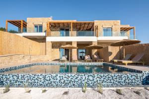 une maison avec une piscine entourée de parasols dans l'établissement Alma Natura Villas Falasarna- Aphroditi Villa, à Falasarna