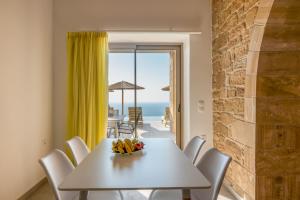 a white dining room with a table and a view of the ocean at Alma Natura Villas Falasarna- Aphroditi Villa in Falasarna