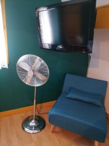Zimmer mit einem Ventilator, einem Stuhl und einem TV in der Unterkunft Chez Sophie et Thibault in Sceaux-du-Gâtinais