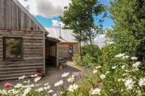 a wooden cabin with flowers in front of it at Lillemor in Okehampton