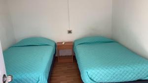 2 camas en una habitación pequeña con mesita de noche en Hostal Viña Del Mar, en Taltal