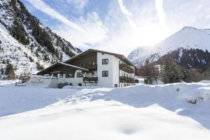 budynek na śniegu z górami w tle w obiekcie Natur Residenz Anger Alm - Adults only w mieście St. Leonhard im Pitztal