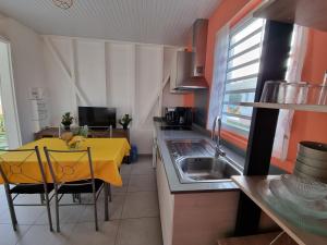 a kitchen with a yellow table and a sink at Le Royal Horizon in Deshaies
