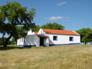 a white house with an orange roof on a field at Casa da Malta do Monte dos Arneiros in Lavre