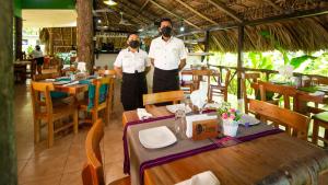 zwei Männer stehen vor einem Tisch in einem Restaurant in der Unterkunft Hotel La Aldea del Halach Huinic in Palenque