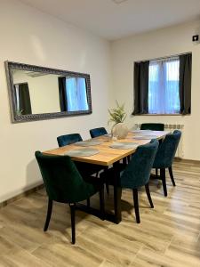 a dining room table with green chairs and a mirror at Prenociste kod Brana in Čačak
