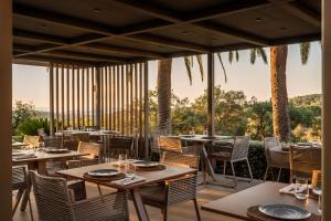 un restaurant avec des tables, des chaises et des palmiers dans l'établissement Sant Pere del Bosc Hotel & Spa - Adults Only, à Lloret de Mar