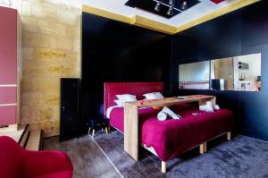 a bedroom with a red bed with a table at Mieuxqualhotel jacuzzi privatif Love room in Bordeaux