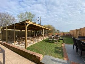 een patio met tafels en stoelen onder een houten paviljoen bij The Six Bells in Newbury