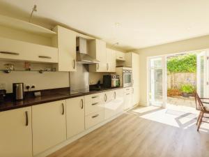 a kitchen with white cabinets and a large window at Pears Grove - Southbourne in Emsworth