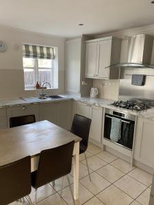 a kitchen with white cabinets and a wooden table with chairs at Waters Reach in Abersoch