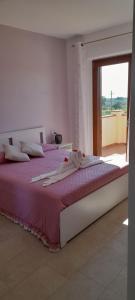 - une chambre avec un lit doté de draps violets et une fenêtre dans l'établissement Agriturismo IL VECCHIO OLIVO, à Castagneto Carducci