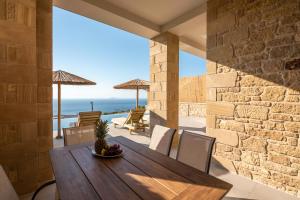 a dining room with a table and a stone wall at Alma Natura Villas Falasarna- Aphroditi Villa in Falasarna