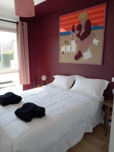 una camera da letto con un letto bianco e un dipinto sul muro di Le gîte de la salicorne a Marck