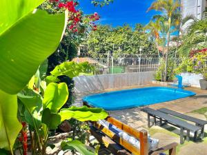 a swimming pool with two benches and a sidx sidx sidx at Pousada Flor de Ponta Negra in Natal