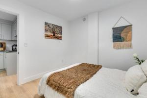 a white room with a bed and two paintings on the wall at Guest suite in South Surrey in Surrey