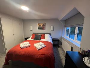 een slaapkamer met een rood bed en handdoeken erop bij The Six Bells in Newbury