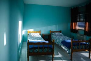 two beds in a room with blue walls at Pousada Guarida in Rio Grande