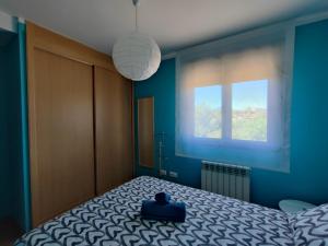Dormitorio azul con cama y ventana en El Mirador de Murillo en Murillo de Río Leza