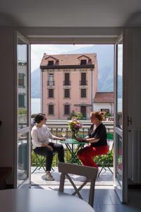 zwei Frauen sitzen an einem Tisch auf einem Balkon in der Unterkunft Casa Aidee in Varenna