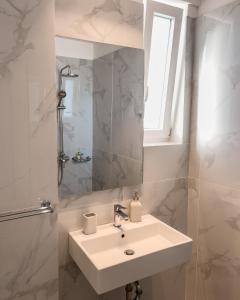 W białej łazience znajduje się umywalka i lustro. w obiekcie TIKI BEACH STUDIOS w mieście Nea Makri