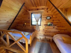 1 dormitorio en una cabaña de madera con cama y ventana en Brvnare Na Brdu en Šljivovica