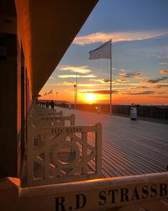 a sunset on a pier with benches on a boardwalk at Évasion à Deauville in Deauville