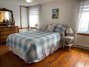 a bedroom with a bed with a plaid blanket and two windows at gite cap a l aigle in La Malbaie