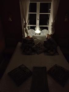 Cama en habitación oscura con ventana en Den Unika Sekelskiftsvåningen., en Norrtälje