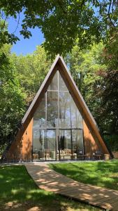ein Glasgebäude mit einem großen Fenster in einem Park in der Unterkunft La Maison Villeneuve - Lodges avec bains nordiques in Donnay