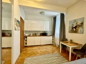 uma cozinha com armários brancos e uma mesa em Cozy Local Naplavka Apartments in Center em Praga