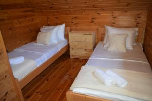 two beds in a room with wooden walls and wooden floors at Vila Bridge Tara in Pljevlja