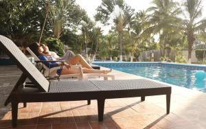 two people sitting in hammocks by a swimming pool at Hotel HF Hacienda San Francisco in Puente Nacional