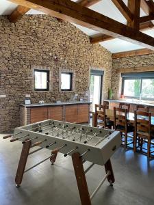 a ping pong table in a room with a stone wall at Belle villa avec piscine intérieure et piscine extérieure Gite Les Aiguiers in Grignan
