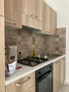La cuisine est équipée de placards en bois et d'un four avec plaques de cuisson. dans l'établissement Sofi House, à Santo Stefano di Camastra