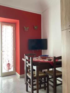 une salle à manger avec un mur rouge, une table et des chaises dans l'établissement Sofi House, à Santo Stefano di Camastra