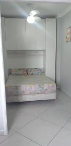 Cama pequeña en habitación con armarios blancos en Apartamento da Flávia, en Praia Grande