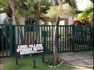 a sign in the grass next to a fence with palm trees at Beira Mar Salvador Bahia Brazil climatizado in Salvador