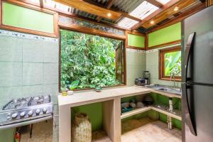 a kitchen with a sink and a large window at casa chilamates in Tortuguero