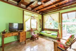 a living room with a television and a desk at casa chilamates in Tortuguero