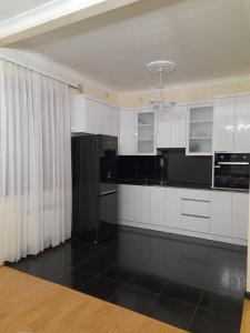 cocina con armarios blancos y suelo negro en D&G guest house, en Yeghegnadzor