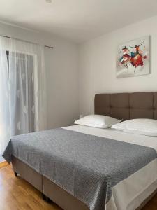 1 dormitorio con 1 cama grande con sábanas blancas en Apartmani Silence, en Rogoznica