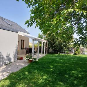 un patio con pérgola blanca y césped verde en Domek przy winnicy 