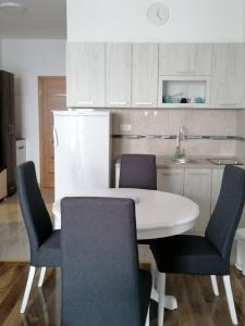 a kitchen with a white table and chairs in a kitchen at Apartman Petar in Nova Varoš