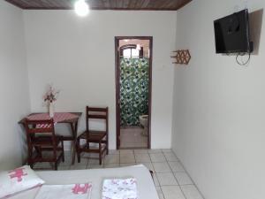 a living room with a table and a television and a table and chairs at Pousada Sol e Verão in São Pedro da Aldeia