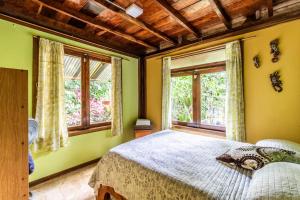 ein Schlafzimmer mit einem Bett und zwei Fenstern in der Unterkunft casa chilamates in Tortuguero